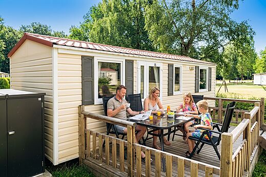 Familie ontbijtend op terras van een stacaravan op camping CAPFUN Tecklenburg.