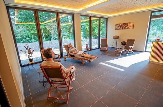 Lichte ontspanningsruimte met stoelen en uitzicht op de natuur op camping CAPFUN Tecklenburg in Tecklenburg-Leeden (49).