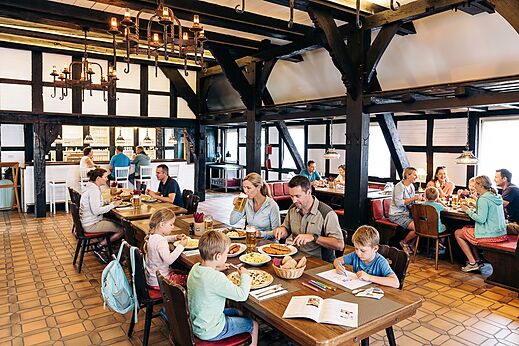 Families en koppels dineren in het rustieke restaurant van camping CAPFUN Tecklenburg in Tecklenburg-Leeden (49).