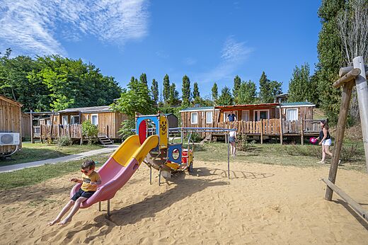 Speeltuin met glijbaan en stacaravans op camping CAPFUN Temps Libre in BOUGE CHAMBALUD.