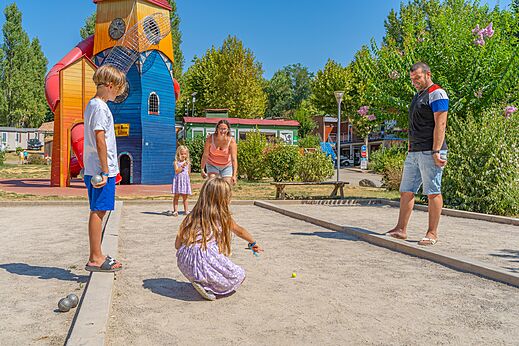 Familie speelt jeu de boules op de baan, met speeltuin op camping CAPFUN Temps Libre in BOUGE CHAMBALUD (38).