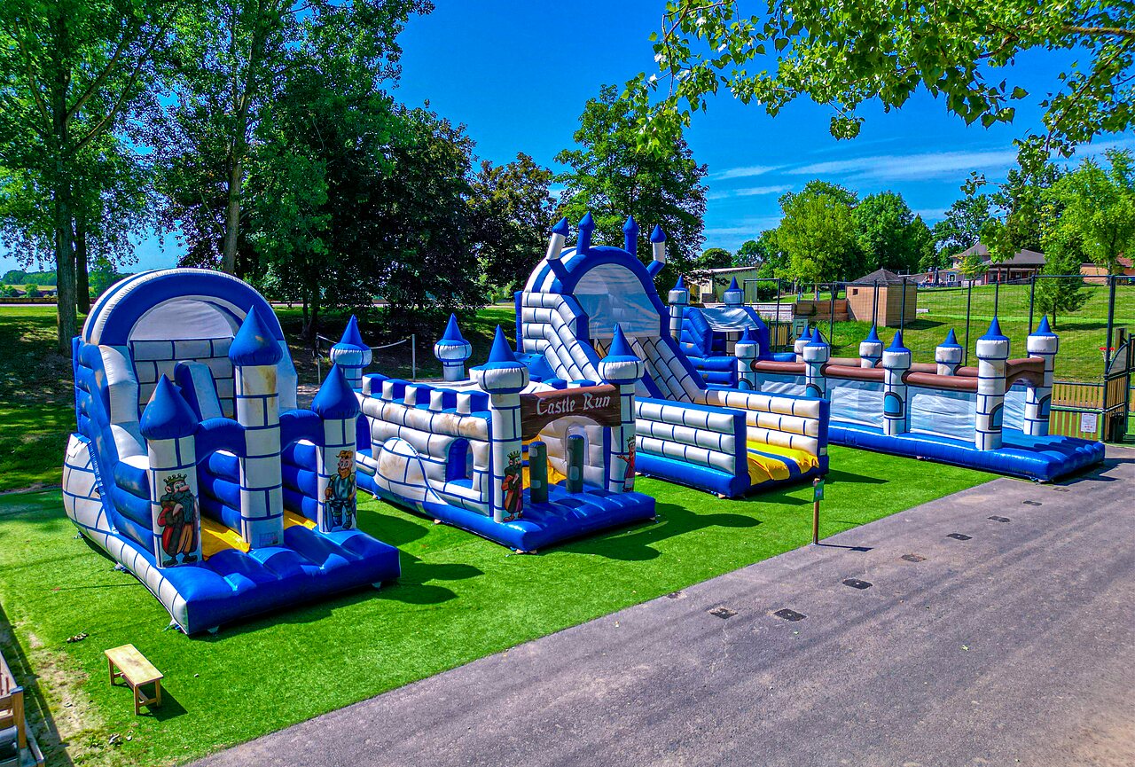 Opblaasbare springkastelen en speelparcours voor kinderen op groen gras bij camping CAPFUN Tensch Jolie in Grostenquin (57).