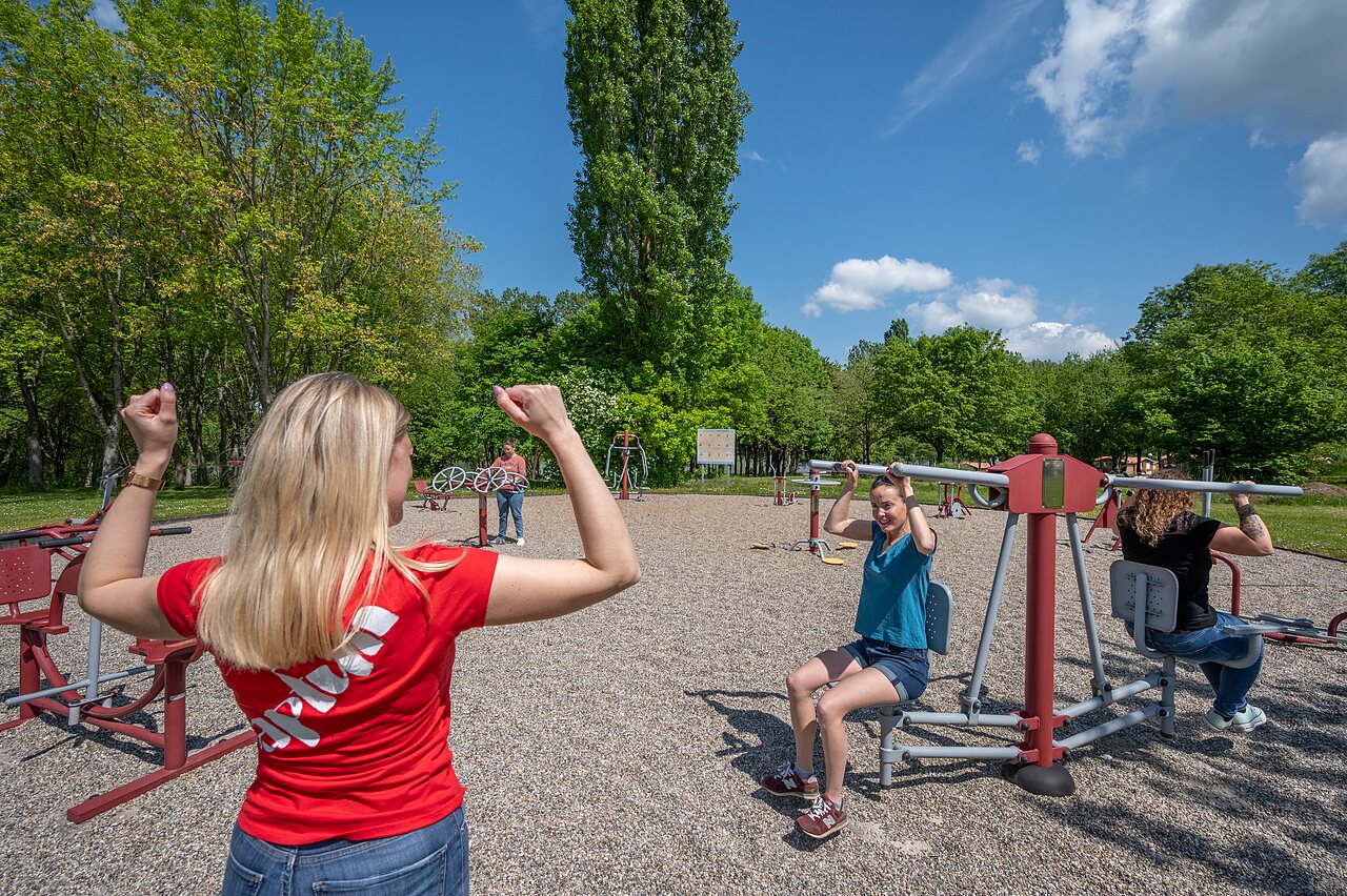 Mensen gebruiken outdoor fitnessapparatuur op camping CAPFUN Tensch Jolie in Grostenquin (57).