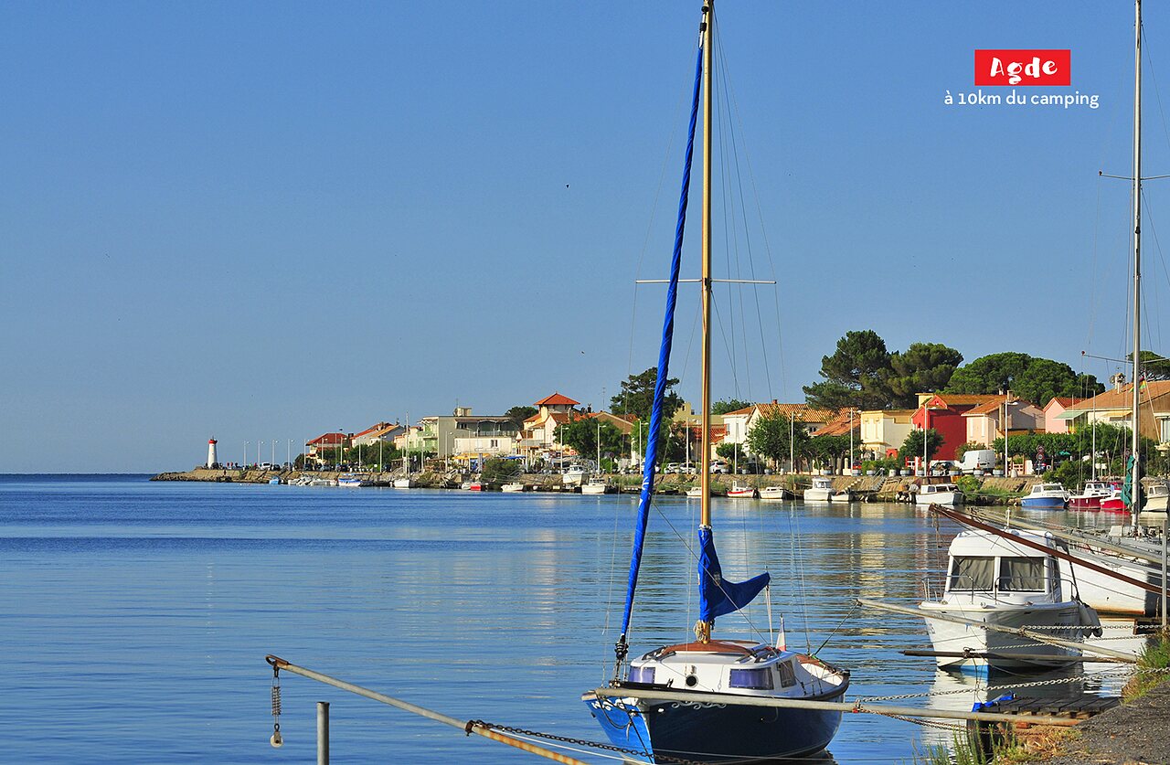 Haven van Agde met zeilboten, kleurrijke huizen en vuurtoren, nabij Marseillan Plage.