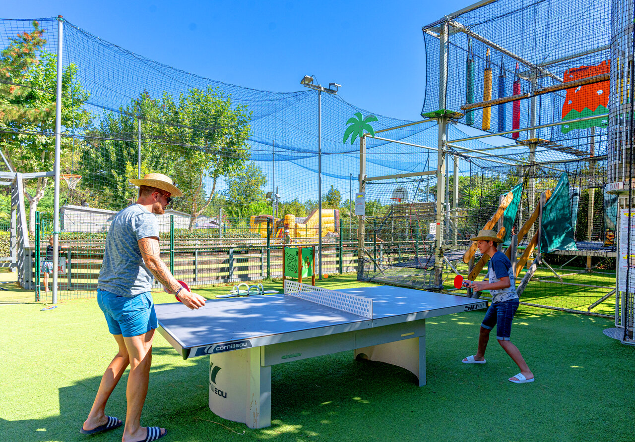 Vader en zoon spelen tafeltennis op kunstgras op camping CLICOCHIC Texas in Argel�s sur Mer (66).