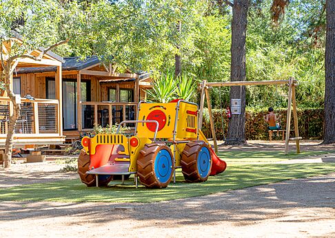 Kinderspeeltuin met tractor en schommel bij de stacaravans op camping CLICOCHIC Texas in Argelès sur Mer (66).