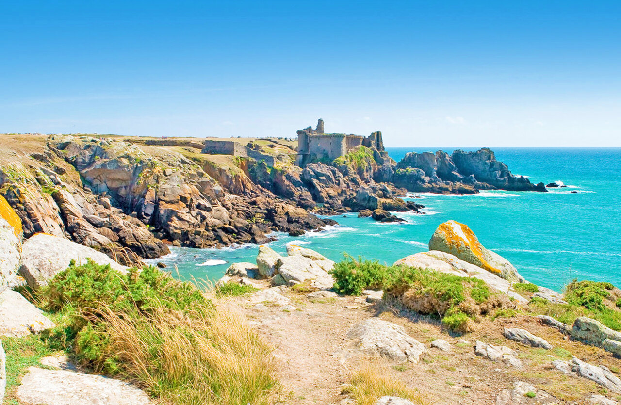 Rotsachtige kliffen, turquoise zee en historische ru�nes op camping CLICOCHIC Plage des Tonnelles.