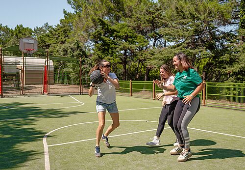 Vrouwen basketballen op multisportterrein op camping CLICOCHIC Plage des Tonnelles in Saint-Jean-de-Monts (85).