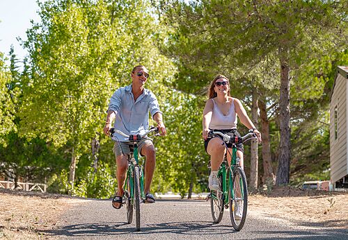 Stel fietst op bomenlaan op camping CLICOCHIC Plage des Tonnelles.