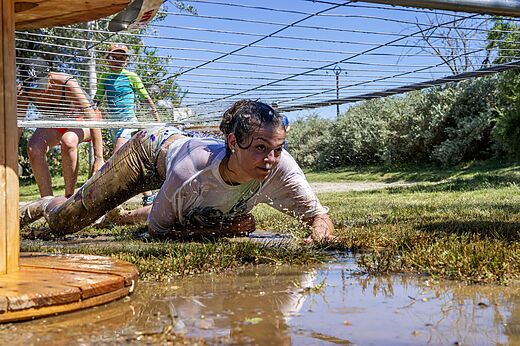 Modderig hindernisparcours, persoon kruipt op camping CAPFUN Tordera-Nacions in Malgrat de Mar.