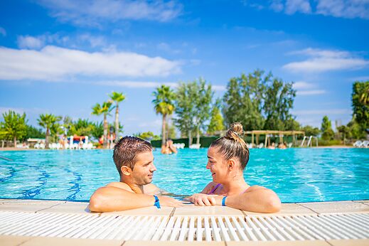 Lachend stel in het buitenzwembad van camping CAPFUN Tordera-Nacions in Malgrat de Mar.