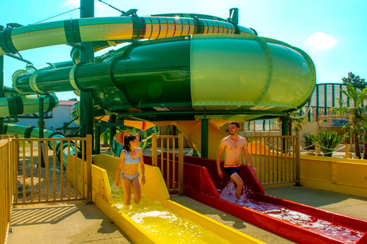 Kleurrijke waterglijbanen en mensen die plezier hebben op camping CAPFUN Celeste in Breuillet (17).