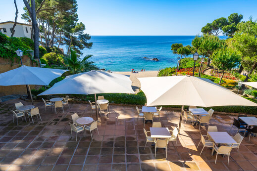 Restaurantterras, tafels, parasols, zee op camping CAPFUN Treumal in Platja d'Aro.