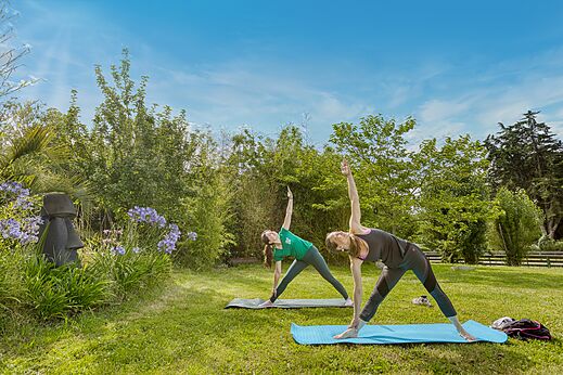 Twee vrouwen beoefenen yoga buiten op camping CLICOCHIC Trois Chênes.