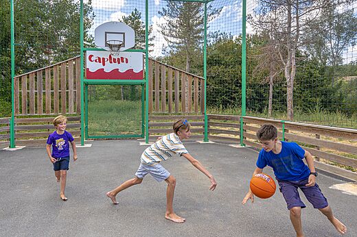Kinderen spelen basketbal op het multisportterrein van camping CAPFUN Ullule in Tournon d'Agenais (47).