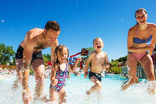 Lachende familie speelt in golfslagbad met glijbanen op camping CAPFUN Ullule in Tournon d'Agenais (47).