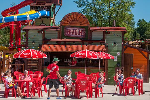 Buitenbar, rode tafels, parasols en glijbanen op camping CAPFUN Ullule.