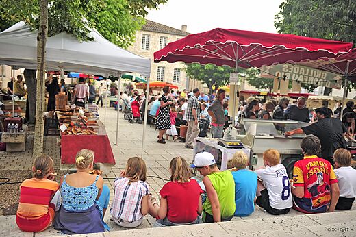 Levendige lokale markt op een dorpsplein, met kraampjes en bezoekers in Lot-et-Garonne.