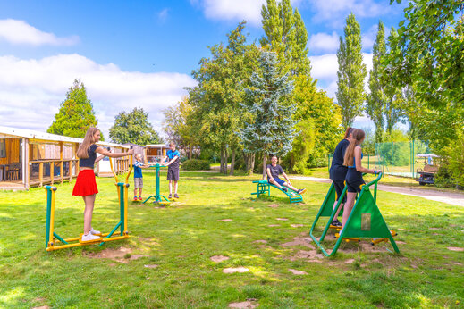 Familie gebruikt outdoor fitnessapparatuur op camping CAPFUN Val d'Authie.