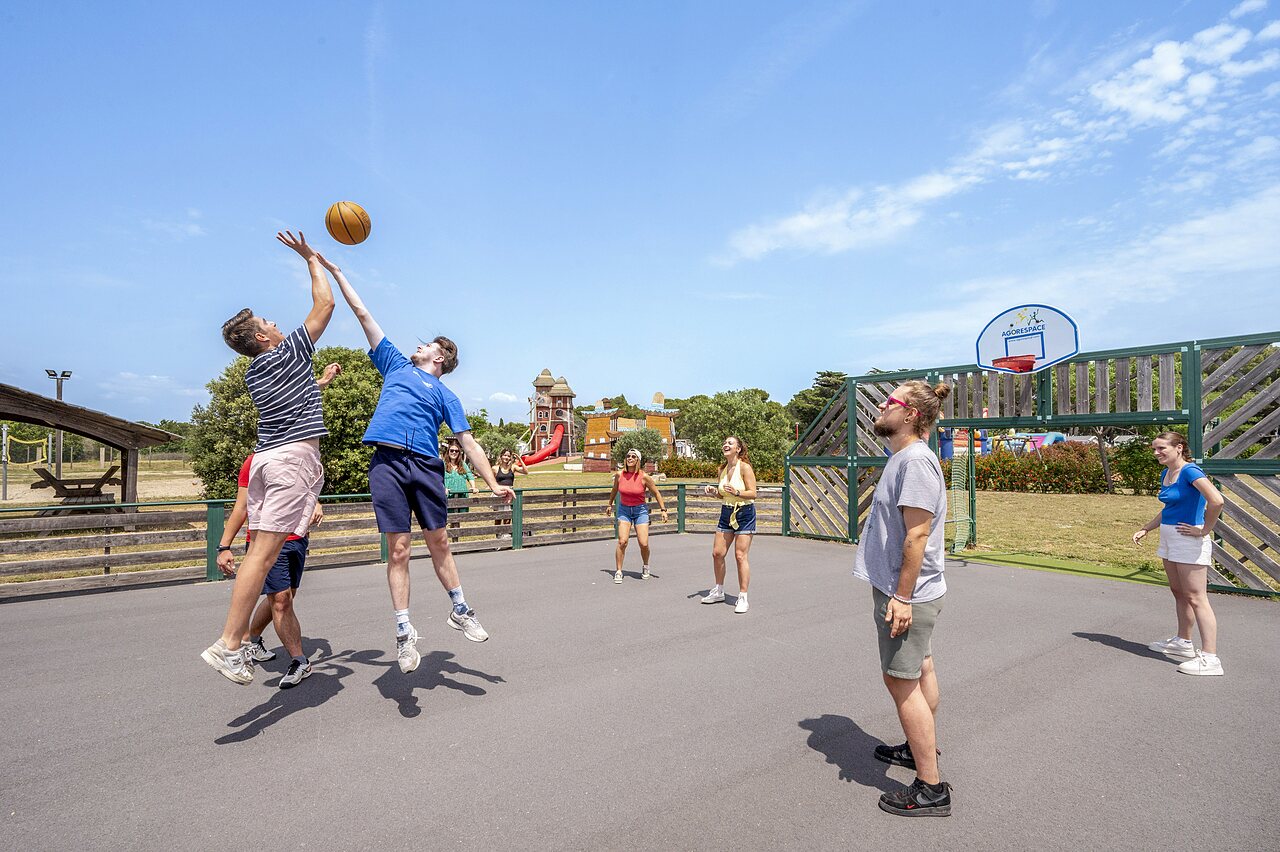 Multisportterrein met jongeren die basketballen op camping CAPFUN Vignes d'Or in Serignan.