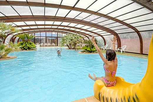 Overdekt zwembad met glijbaan en kinderen op camping CAPFUN Vignes d'Or in Serignan