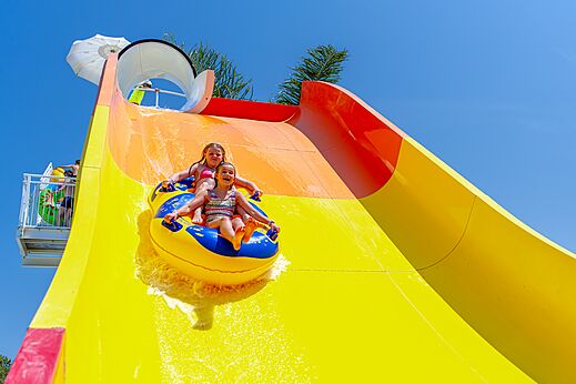 Twee kinderen op band glijden van een reuzenglijbaan op camping CAPFUN Vignes d'Or in Serignan.