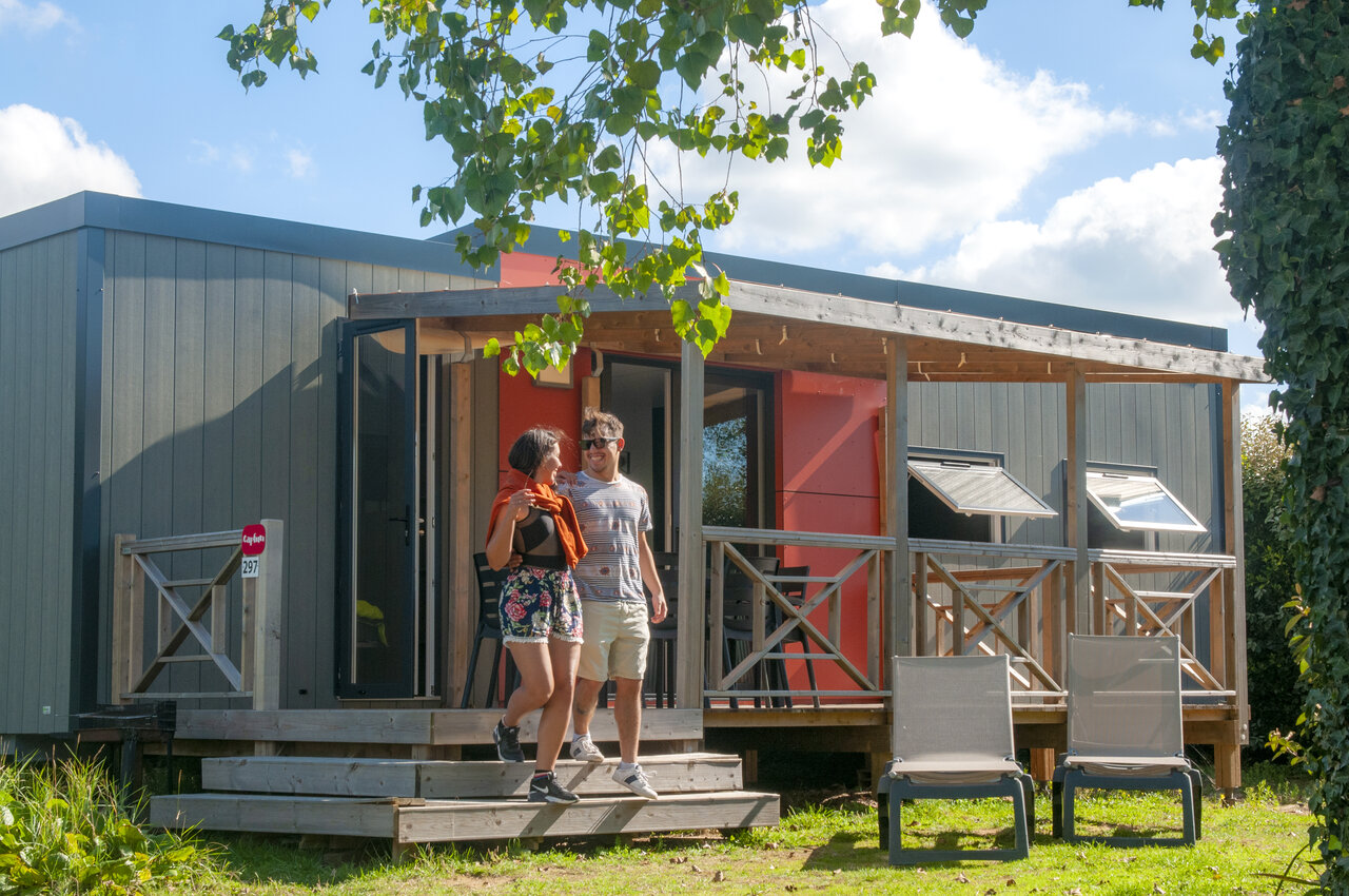 Moderne stacaravan en lachend stel op het terras op camping CAPFUN Vikings in Saint Jean de la Rivi�re (50).