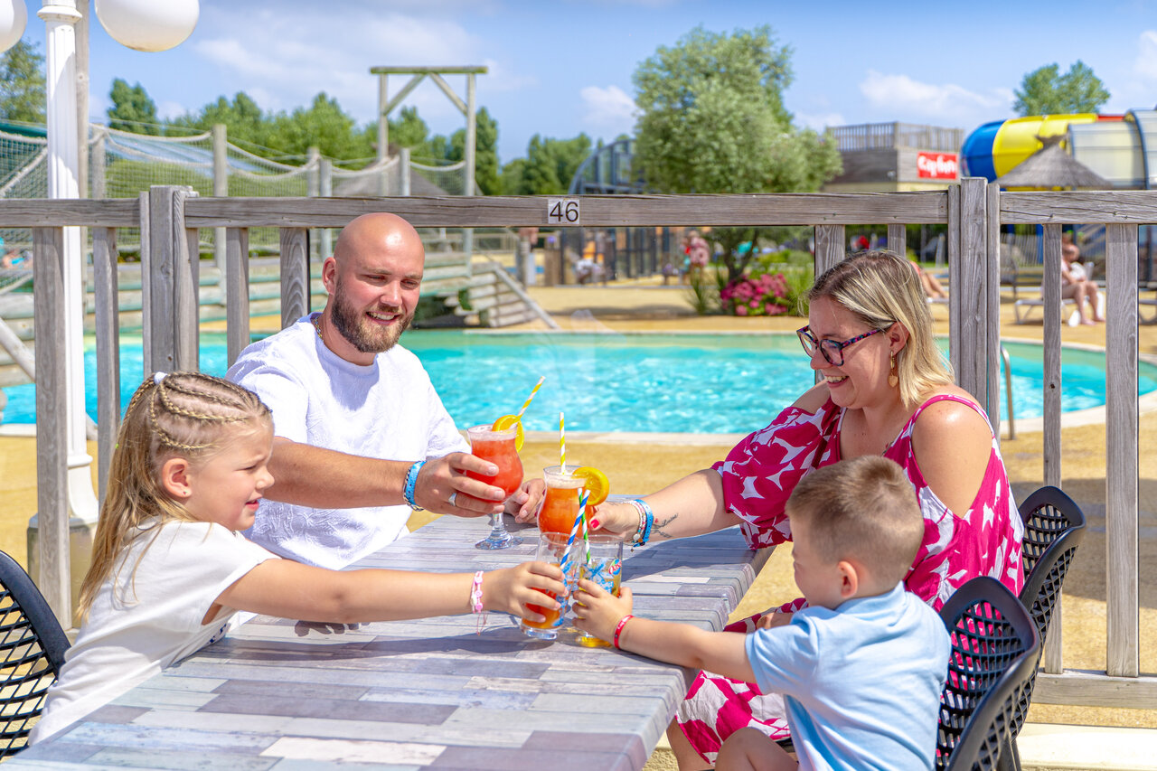 Familie met drankjes aan het zwembad van camping CAPFUN Vikings in Saint Jean de la Rivi�re (50).