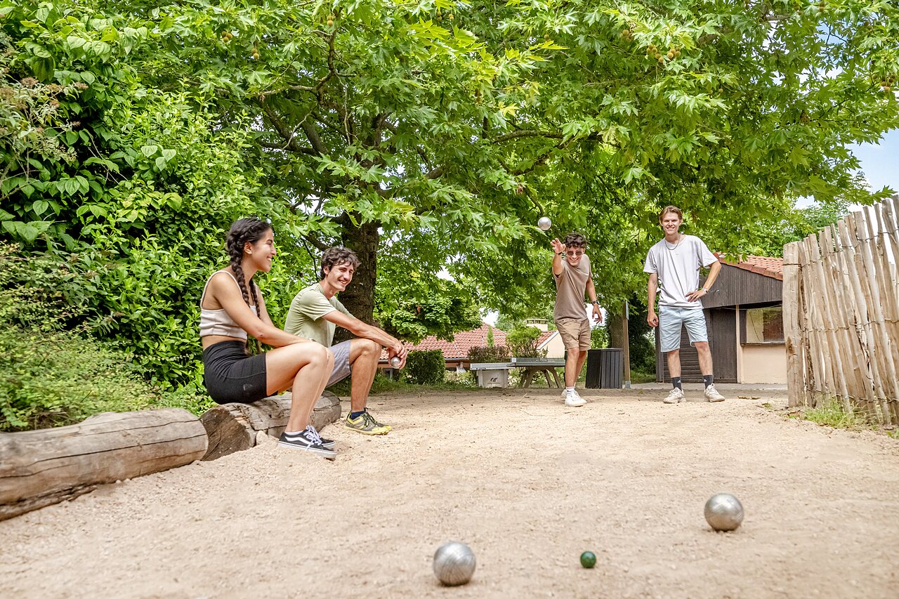 Jongeren spelen jeu de boules op een schaduwrijk terrein op camping CLICOCHIC Village des Meuniers in Dompierre-les-Ormes (71).