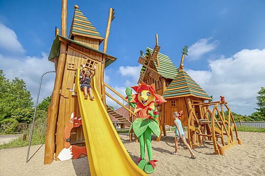 Thematische speeltuin met glijbaan en kinderen op camping CLICOCHIC Village des Meuniers in Dompierre-les-Ormes (71).