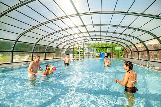 Overdekt zwembad met familie en waterglijbanen op camping CLICOCHIC Village des Meuniers.