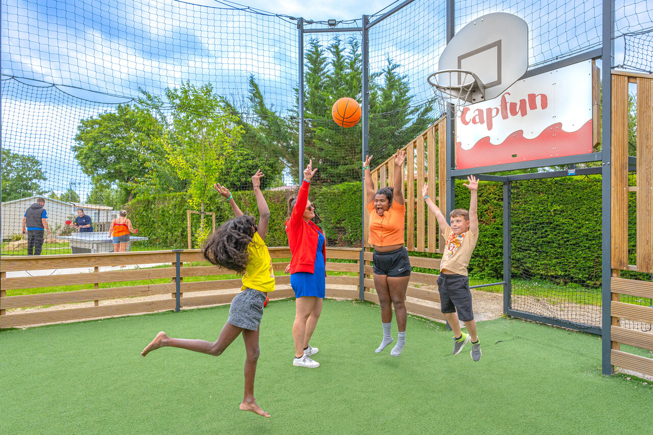 Kinderen en volwassenen basketballen op multisportterrein op camping CAPFUN Le Village Parisien in VARREDDES (77).