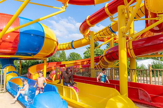 Kleurrijke waterglijbanen en waterspellen op camping CAPFUN Le Village Parisien.