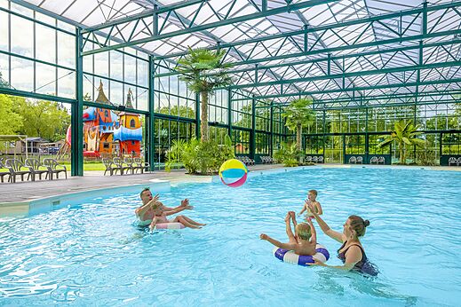 Overdekt zwembad, familie spelend met bal, camping CAPFUN Vlinderloo in Enschede.