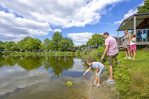 Familie vist met schepnet en hengel bij vijver, camping CAPFUN Vlinderloo Enschede.