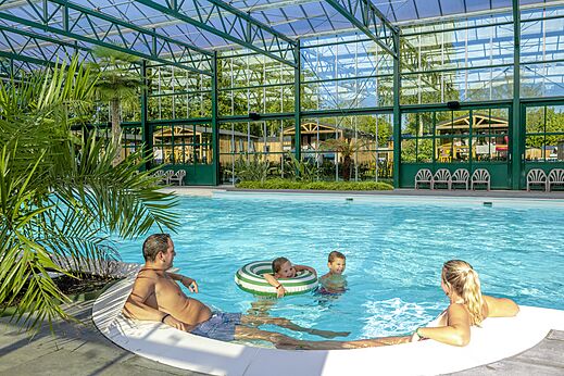 Familie genietend van het overdekte zwembad op camping CAPFUN Vlinderloo in Enschede.