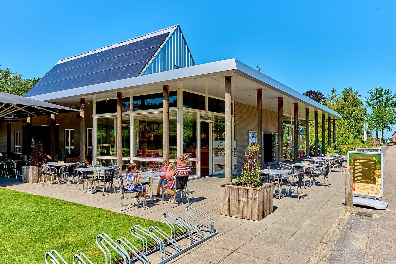 Zonnig restaurantterras, gezin, zonnepanelen op camping CAPFUN De Waldsang in Bakkeveen.