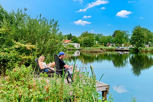 Koppel vist en leest aan meer, weelderige natuur op camping CAPFUN De Waldsang in Bakkeveen.