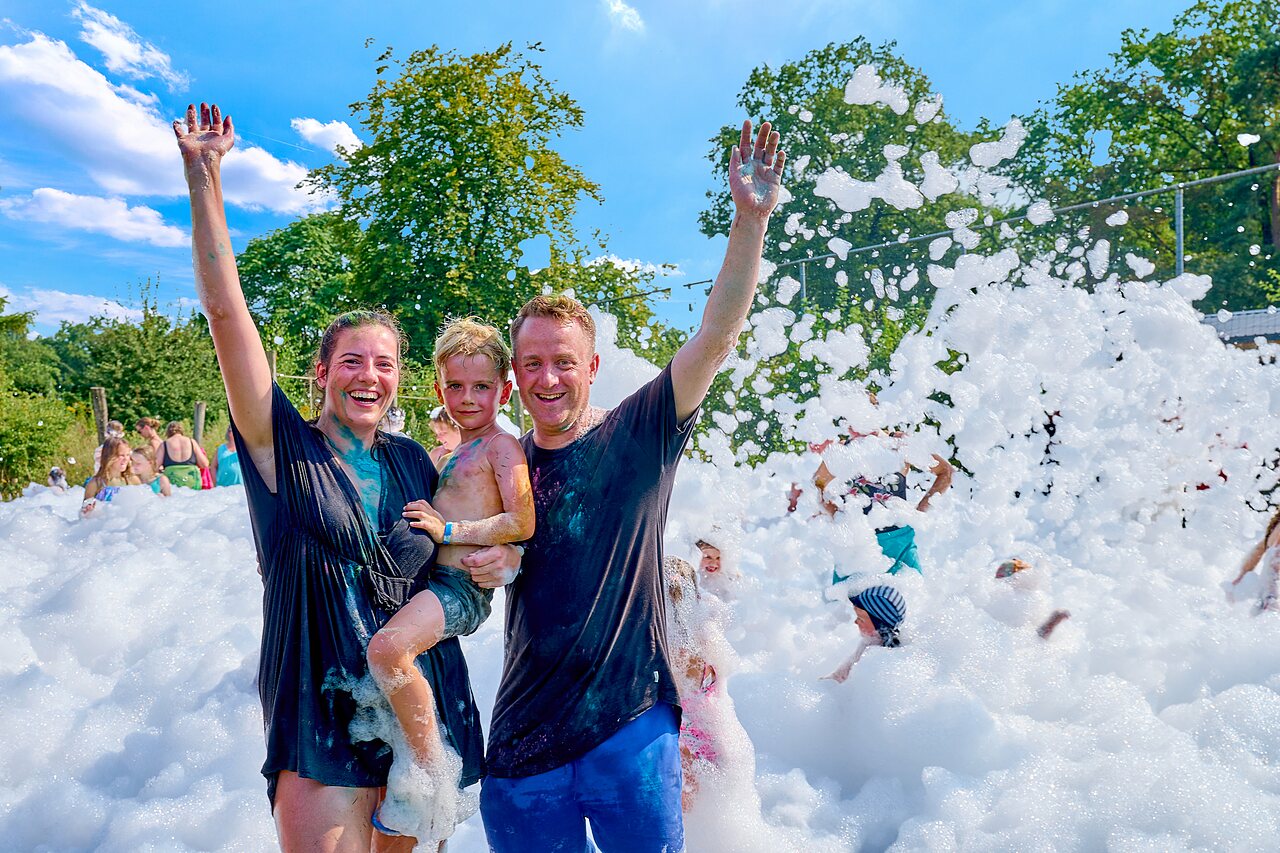 Lachende familie genietend van een vrolijk schuimfeest op camping CAPFUN Wieskamp in Winterswijk Henxel.