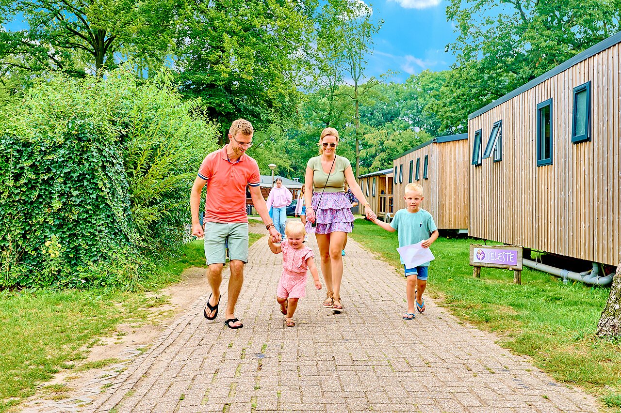 Familie met kinderen wandelt tussen moderne stacaravans op CAPFUN Wieskamp, Winterswijk Henxel.