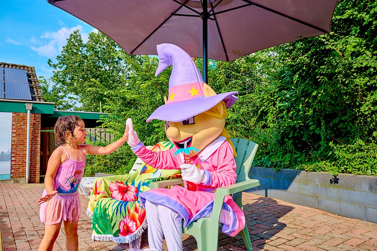 Kind en mascotte onder parasol op camping CAPFUN Wieskamp, Winterswijk Henxel.