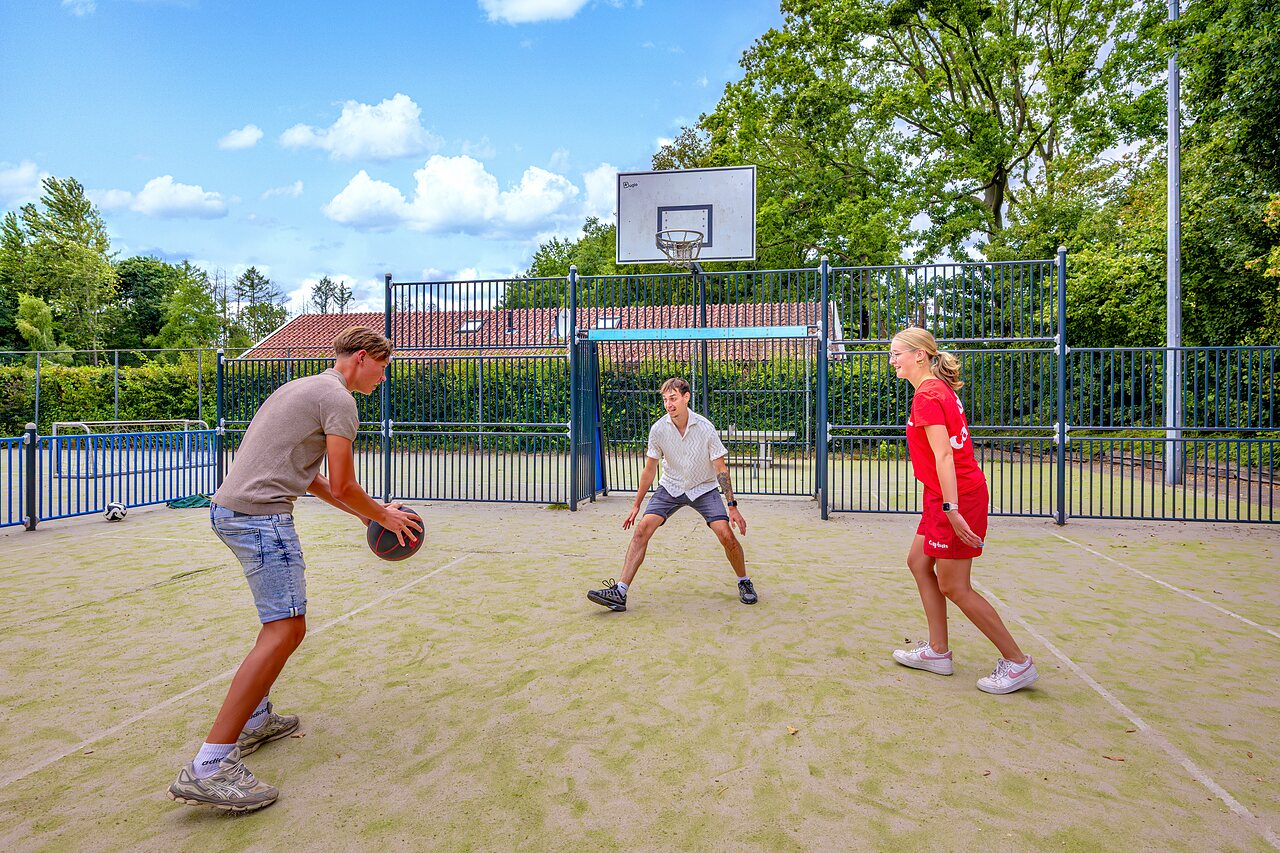Jongeren basketballen op het multisportterrein van camping CAPFUN het Winkel.
