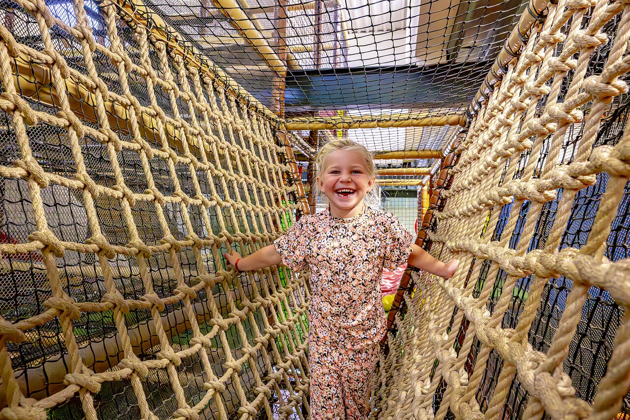 Lachend meisje in touwenparcours op camping CAPFUN het Winkel in Winterswijk.