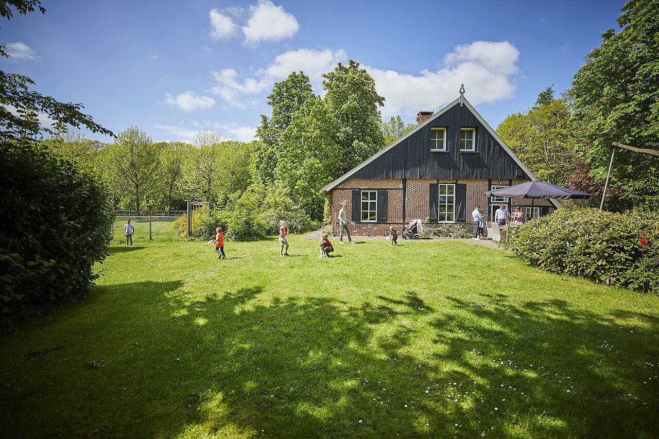 Kinderen spelen op het gazon voor traditioneel gebouw op camping CAPFUN het Winkel te Winterswijk.