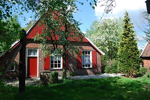 Traditioneel bakstenen huis, rode luiken, bloemrijke tuin op camping CAPFUN het Winkel in Winterswijk.
