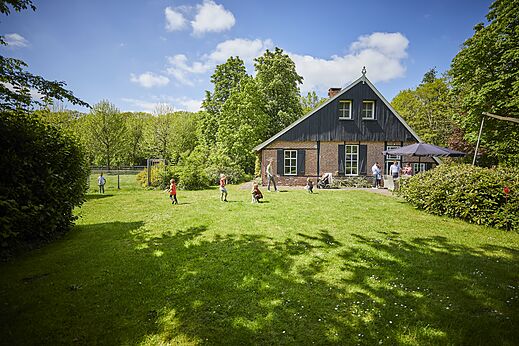 Restaurant met buitenterras en spelende kinderen op het gazon op camping CAPFUN het Winkel in Winterswijk.