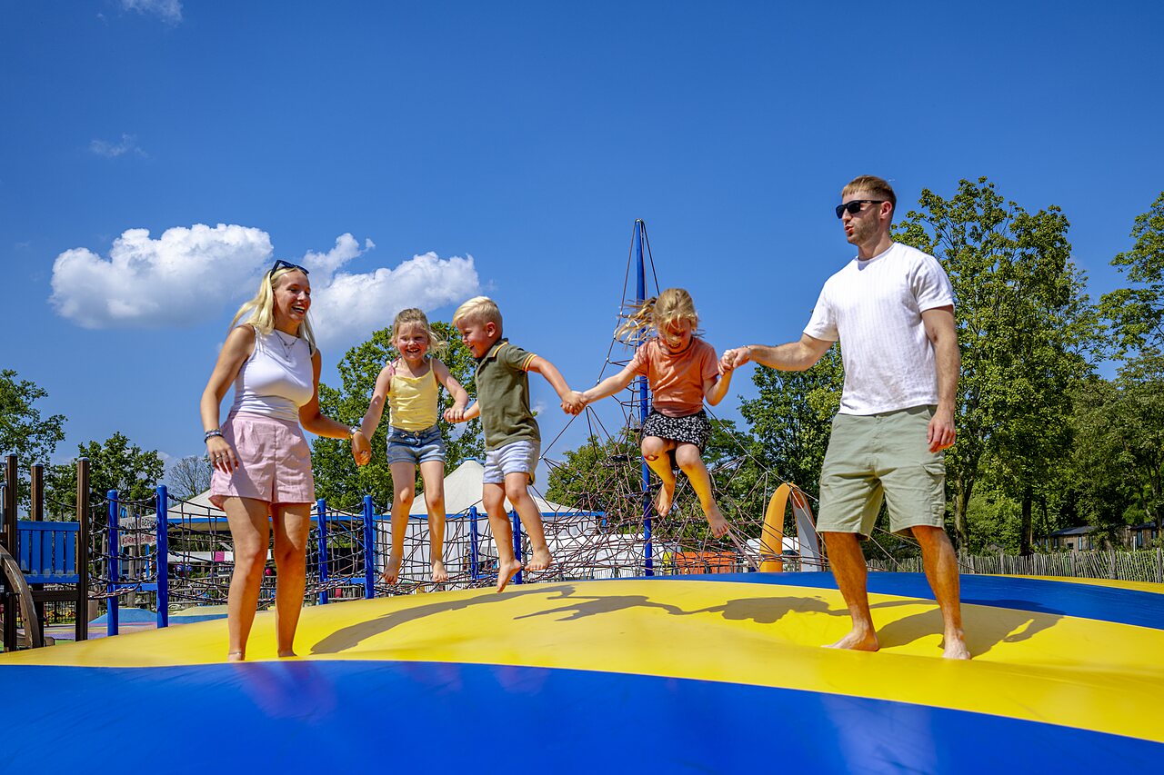 Familie springt op reusachtig springkussen op camping CAPFUN de Wondermolen in Molenschot.