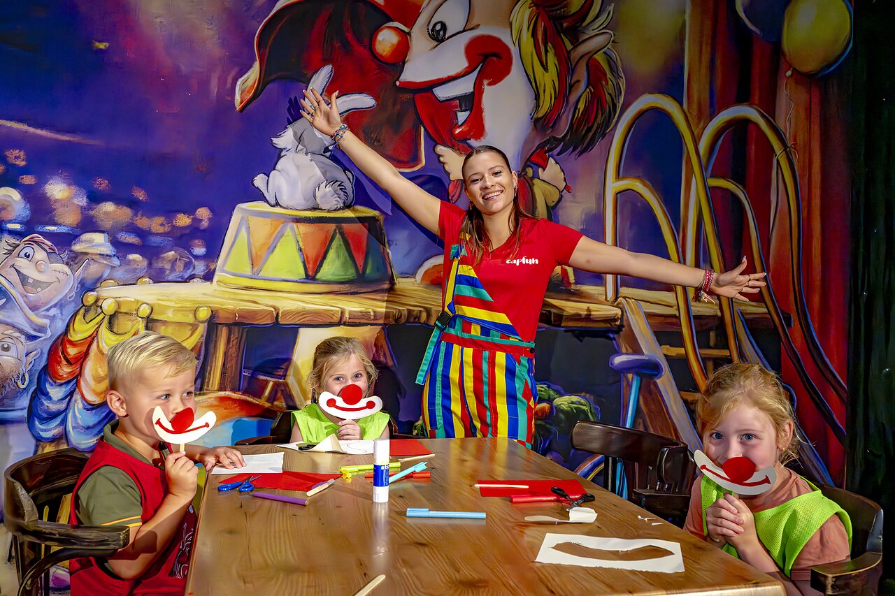 Kinderen maken clownmaskers met de animatrice op camping CAPFUN de Wondermolen in Molenschot.