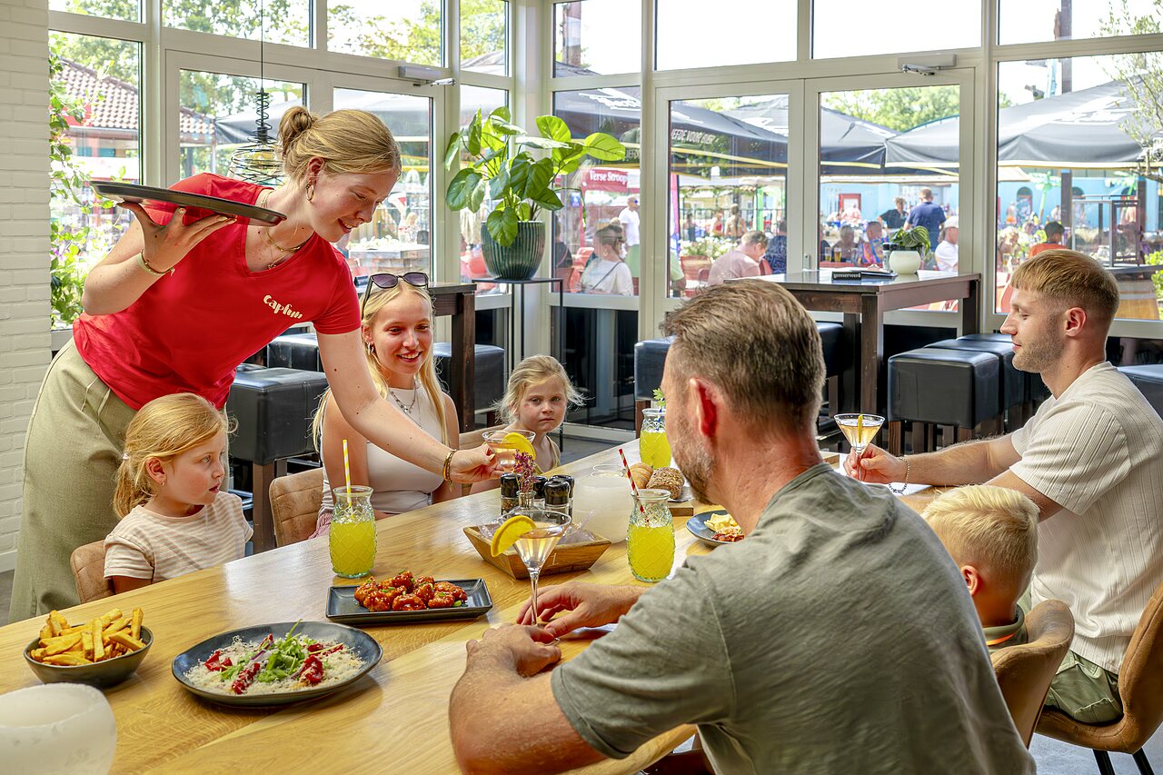 Familie dineert in het restaurant van camping CAPFUN Wondermolen in Molenschot.