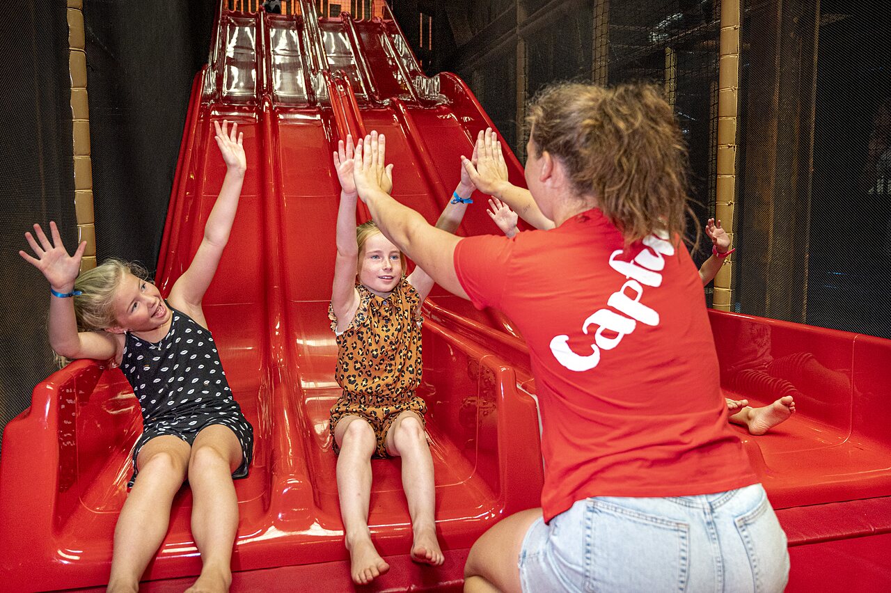Kinderen spelen op een binnenglijbaan met animator op camping CAPFUN de Wondermolen in Molenschot.